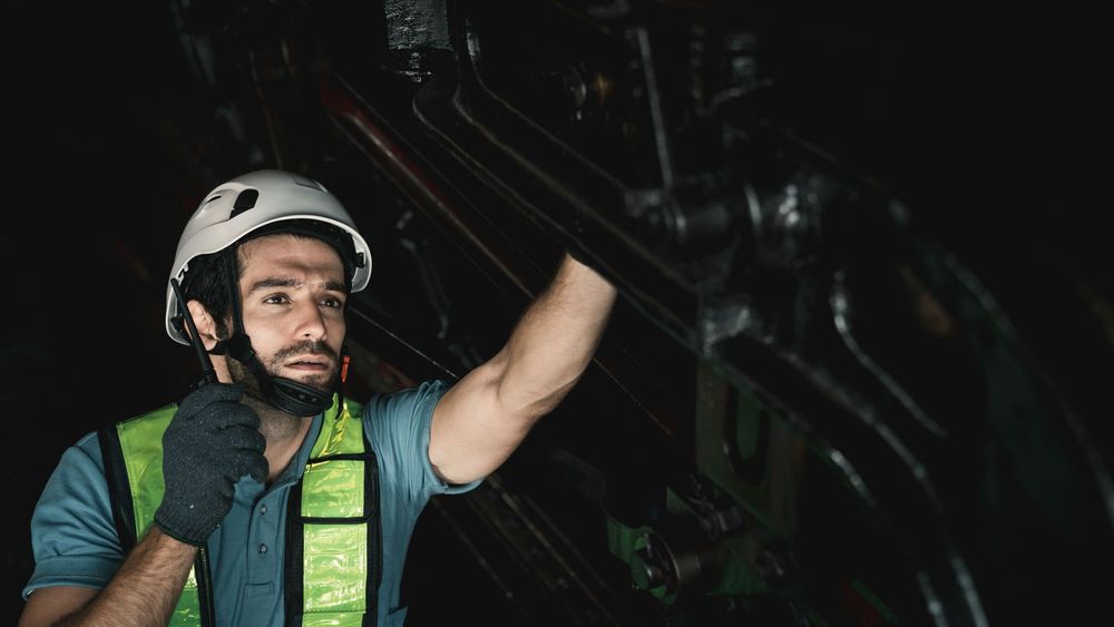 Técnico con casco y guantes inspecciona una máquina