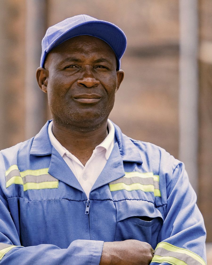 Retrato de un trabajador con gorra y overol con cintas reflectivas, de brazos cruzados