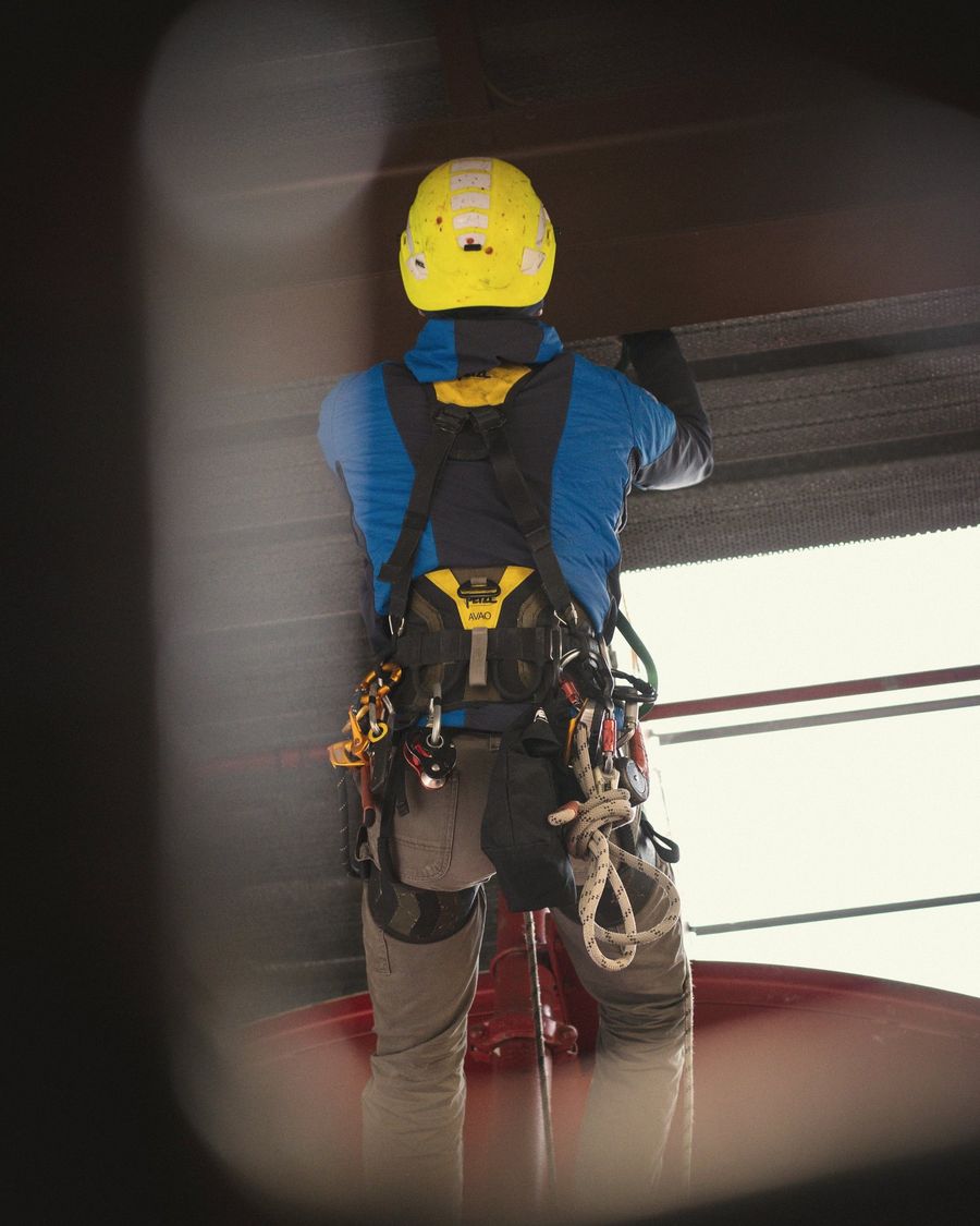 Trabajador con casco amarillo y arnés de seguridad realiza un trabajo en altura