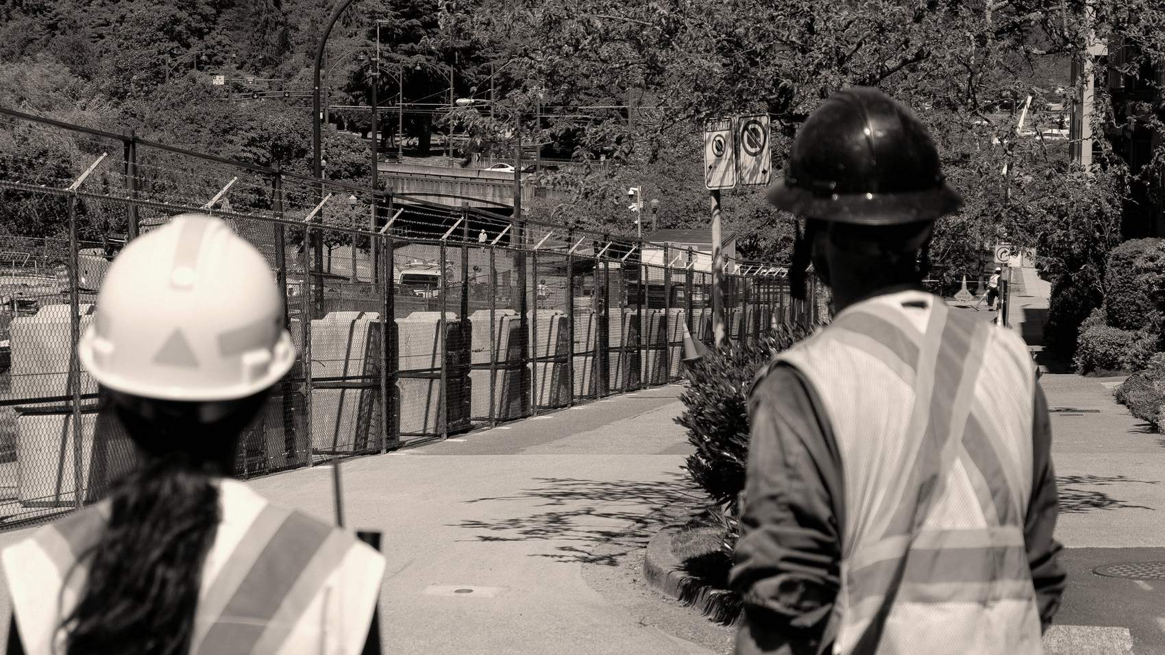 Dos trabajadores con casco y chaleco observan el avance de una obra, de espaldas a la cámara